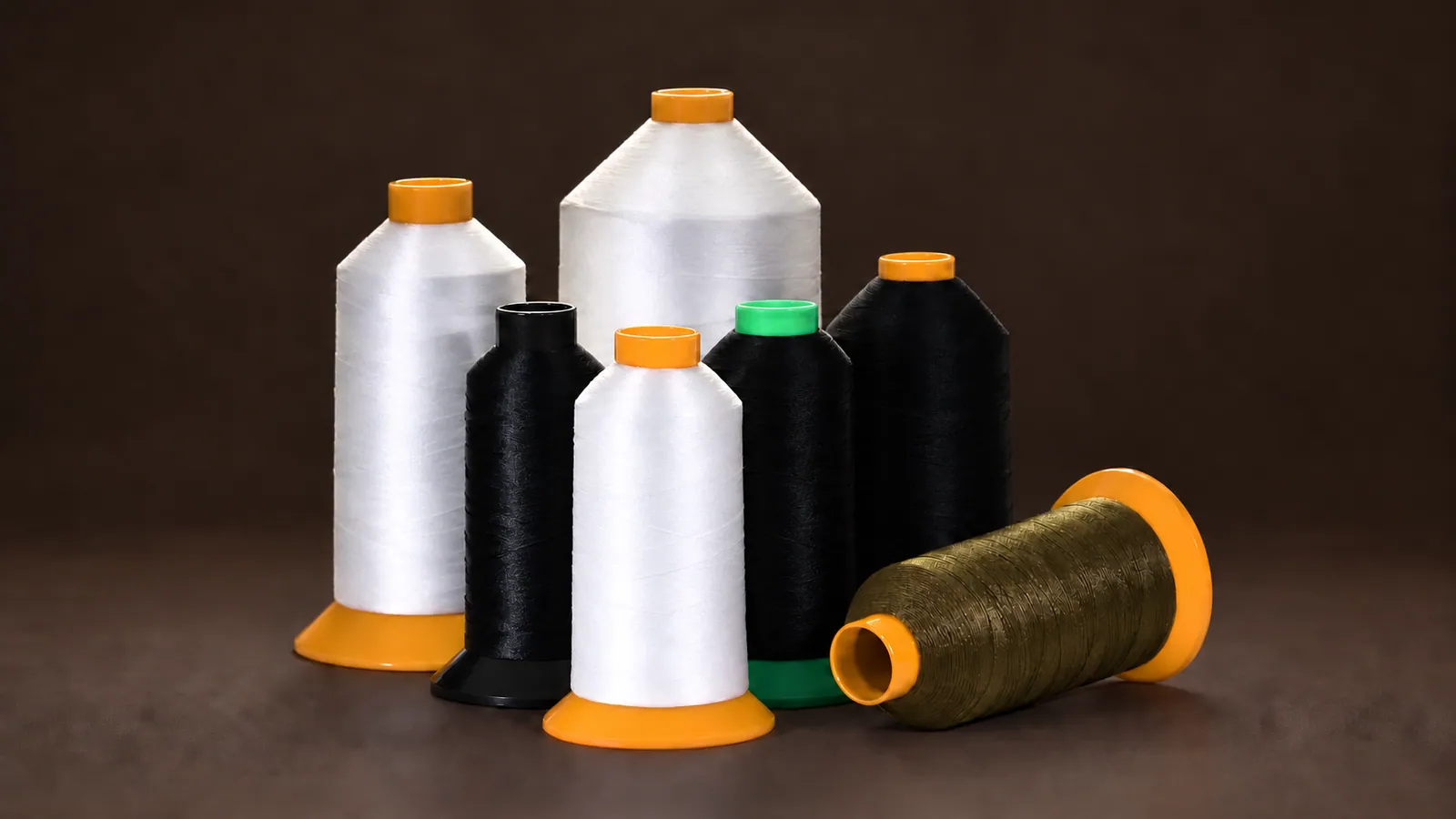 High Tenacity Sewing Thread. Black, white and olive industrial thread cones; labels removed. Source-based AI-edited visualization.